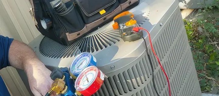 AC Repair - Close up of a technician working on an ac unit. Only the arm is visible along with a tool bag and compression gauges.