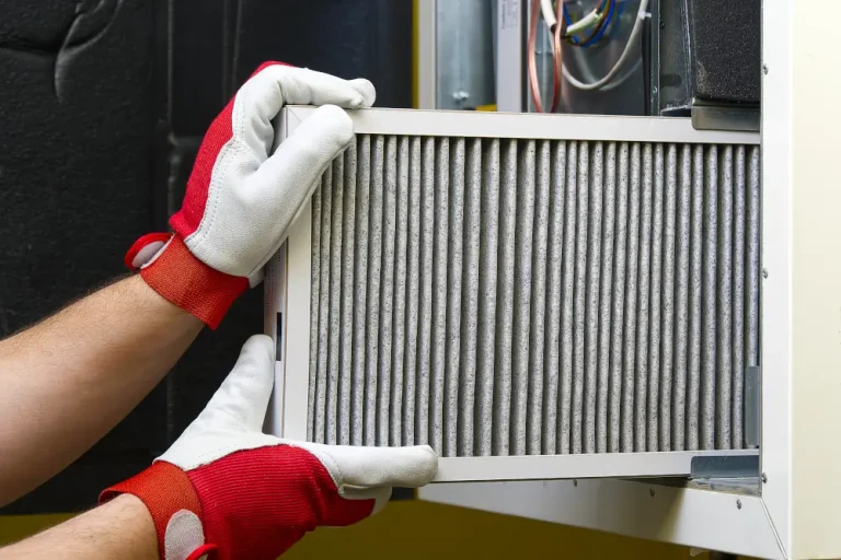 Getting Your Furnace Winter-Ready in London, Ontario: The Essential Guide - Person removing an air filter from a furnace.
