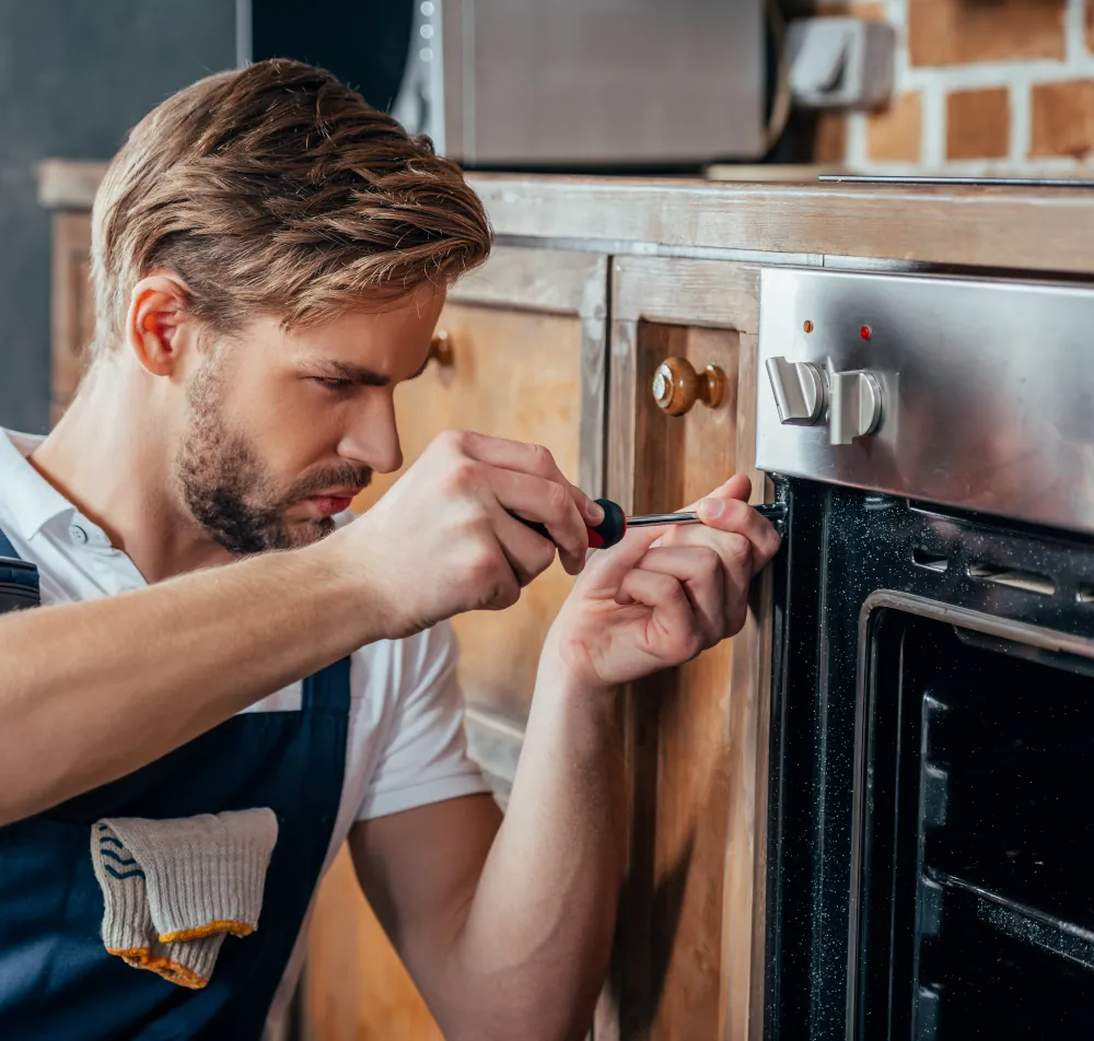 Oven Repair Service in and Around London, ON - Repairman fixing oven with screwdriver.